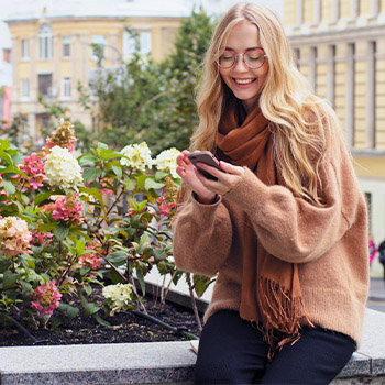 Woman in courtyard smiling at phone