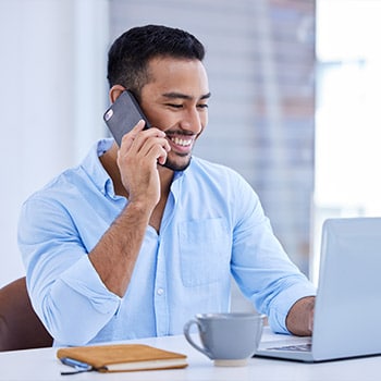 Man on the phone typing on his laptop